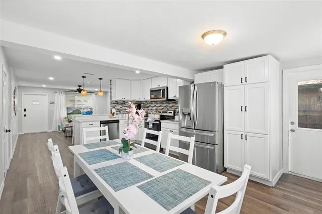 a kitchen with stainless steel appliances granite countertop a refrigerator oven a sink dishwasher and white cabinets with wooden floor