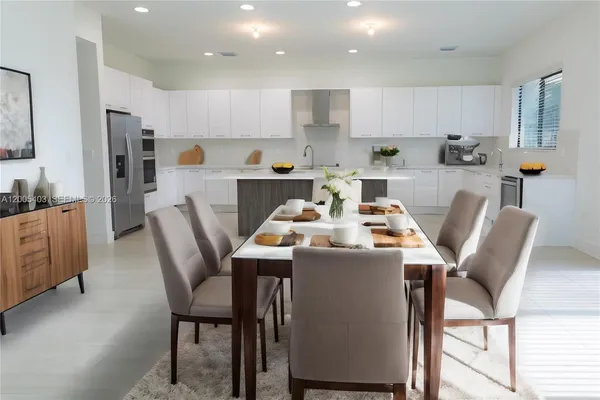 a kitchen with a dining table chairs and refrigerator