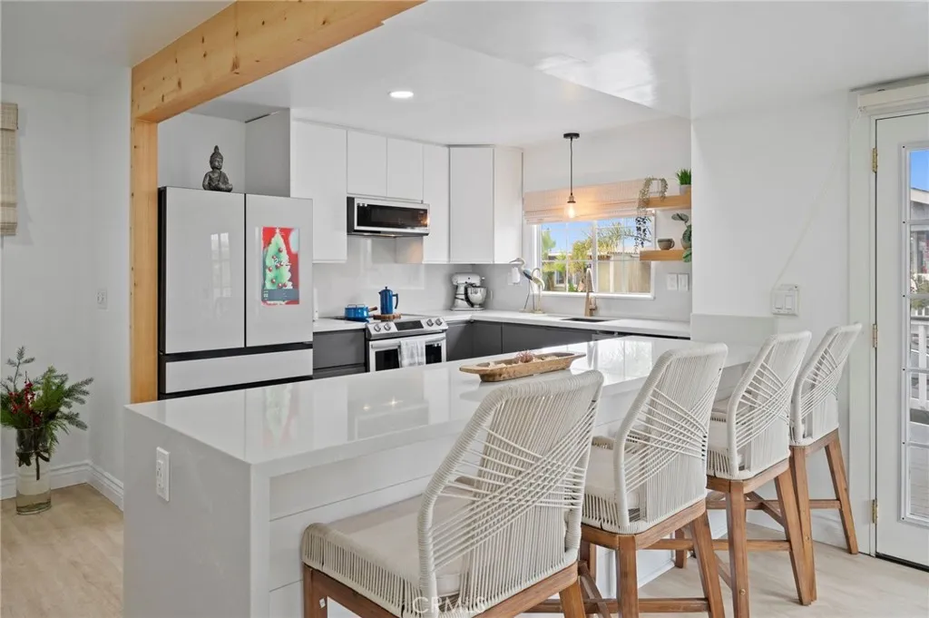 6550 Ponto, Unit 17 Carlsbad, CA 92011 - Photo 15 of 48 a kitchen with stainless steel appliances a white refrigerator oven a sink a dining table and chairs with wooden floor