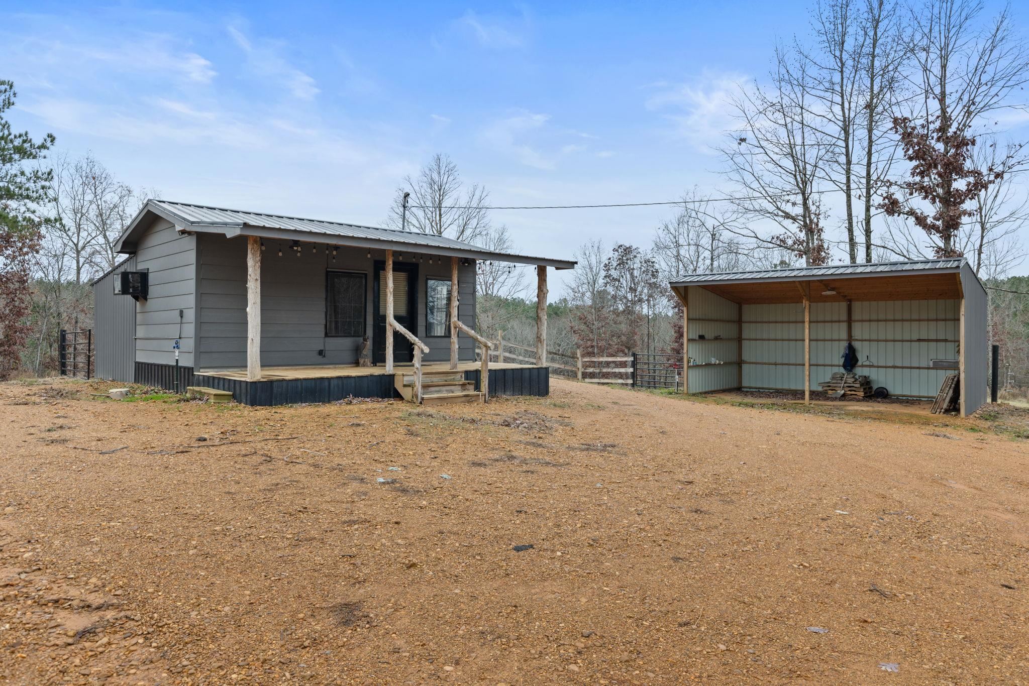 310 County Road 638 Corinth, MS 38834 - Photo 14 of 40 View of front of house featuring a metal roof, a porch, a detached carport, driveway, and an outbuilding