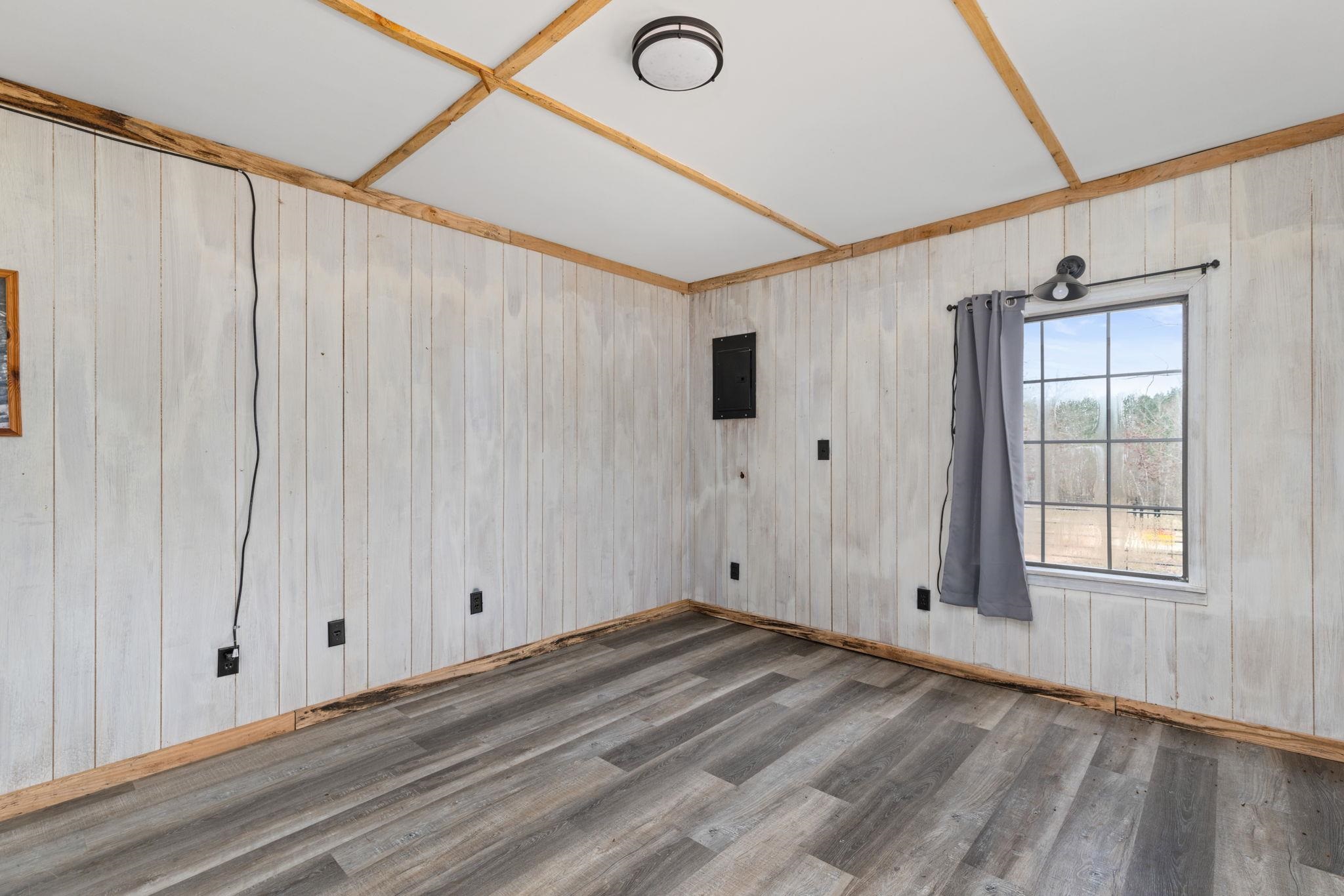 310 County Road 638 Corinth, MS 38834 - Photo 16 of 40 Unfurnished room featuring wood walls, wood finished floors, and electric panel
