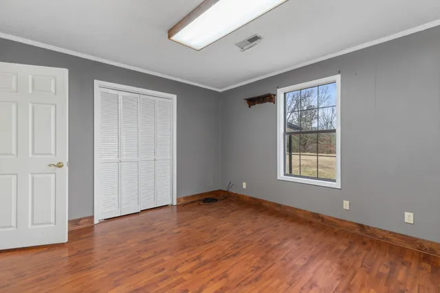 a view of an empty room with wooden floor and a window