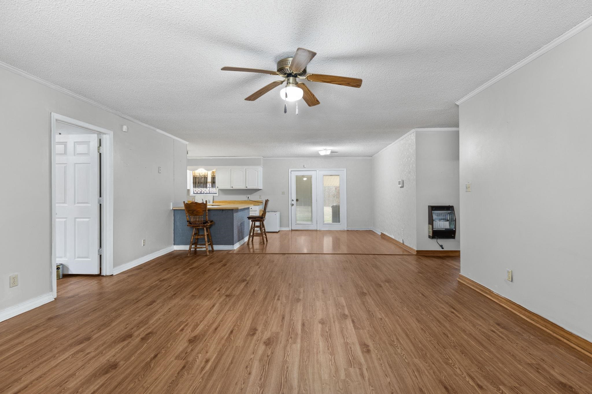 310 County Road 638 Corinth, MS 38834 - Photo 21 of 40 Unfurnished living room with french doors, crown molding, a textured ceiling, a ceiling fan, and heating unit