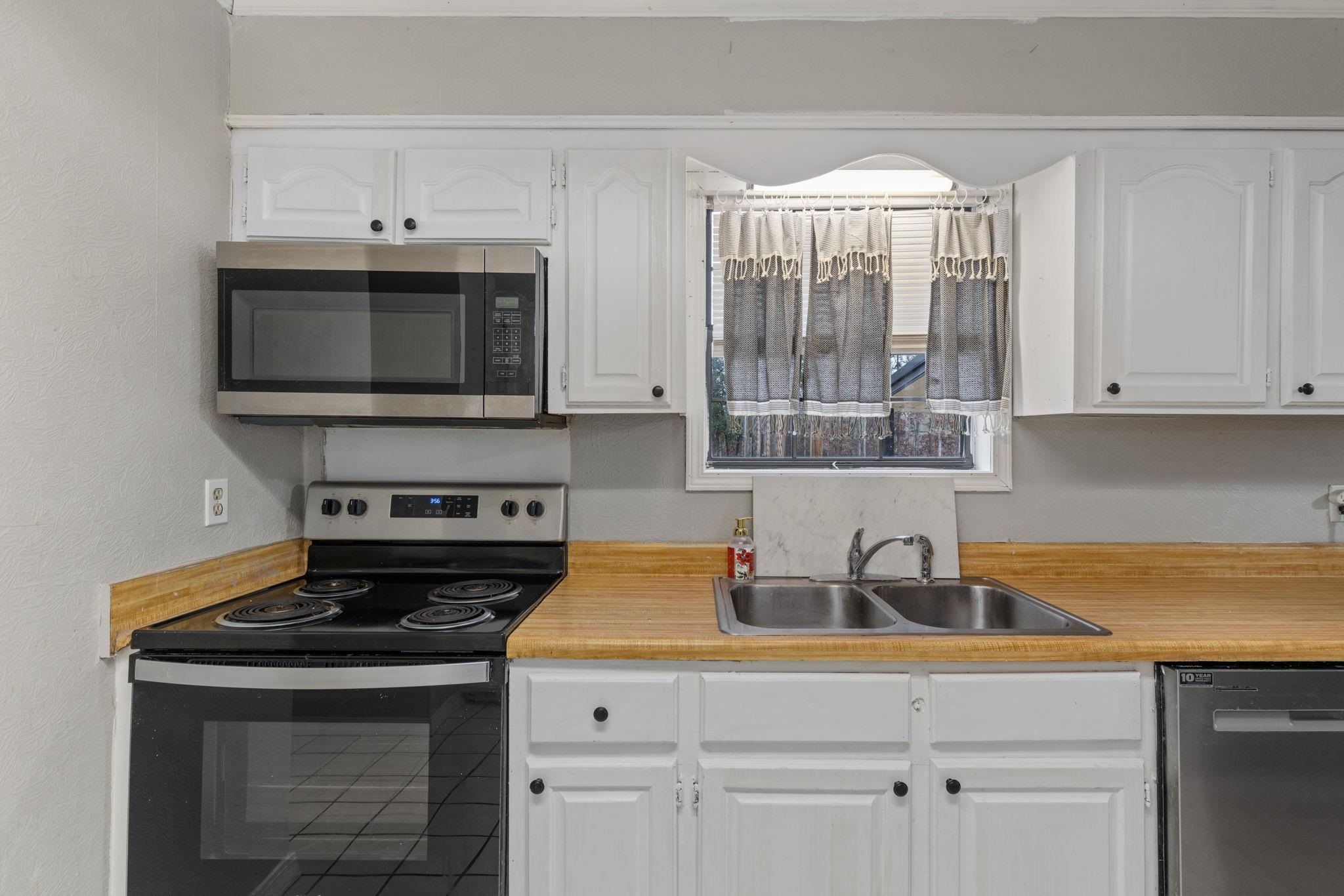 310 County Road 638 Corinth, MS 38834 - Photo 27 of 40 Kitchen with appliances with stainless steel finishes, light countertops, white cabinets, and a textured wall