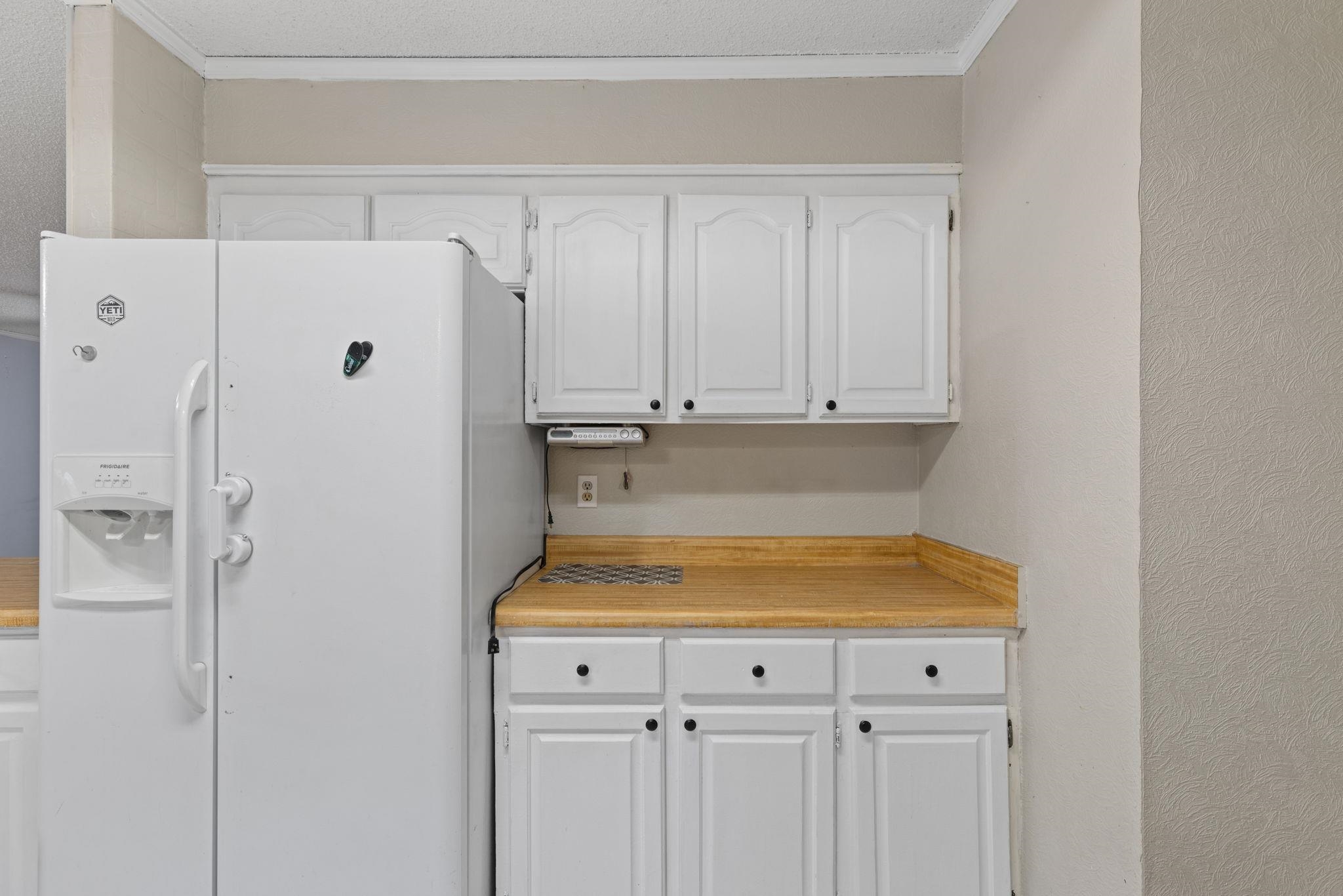 310 County Road 638 Corinth, MS 38834 - Photo 28 of 40 Kitchen with white fridge with ice dispenser, white cabinetry, light countertops, a textured wall, and crown molding