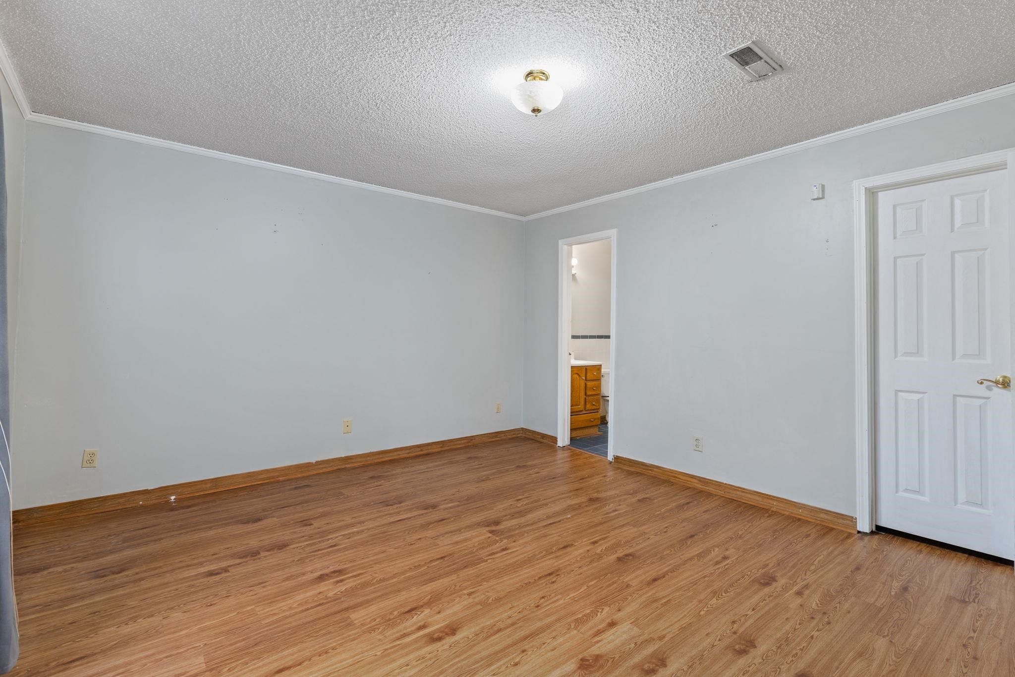 310 County Road 638 Corinth, MS 38834 - Photo 30 of 40 Unfurnished bedroom featuring a textured ceiling, crown molding, light wood-type flooring, and connected bathroom