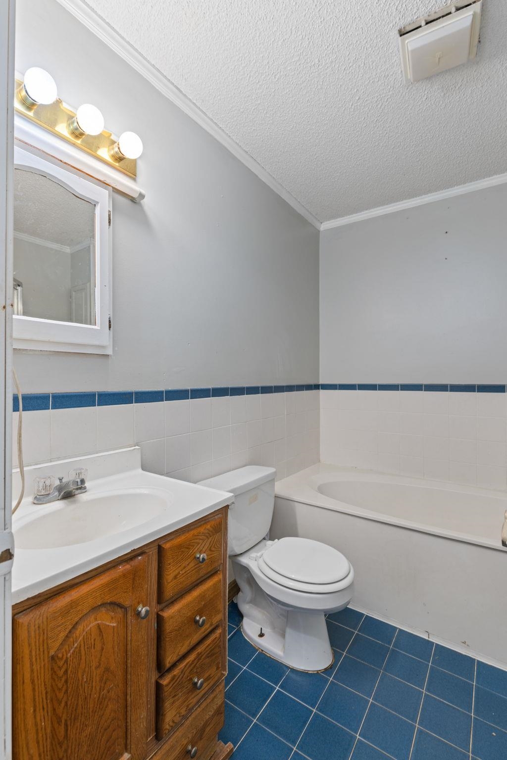 310 County Road 638 Corinth, MS 38834 - Photo 31 of 40 Bathroom with vanity, a textured ceiling, a bath, wainscoting, and tile walls