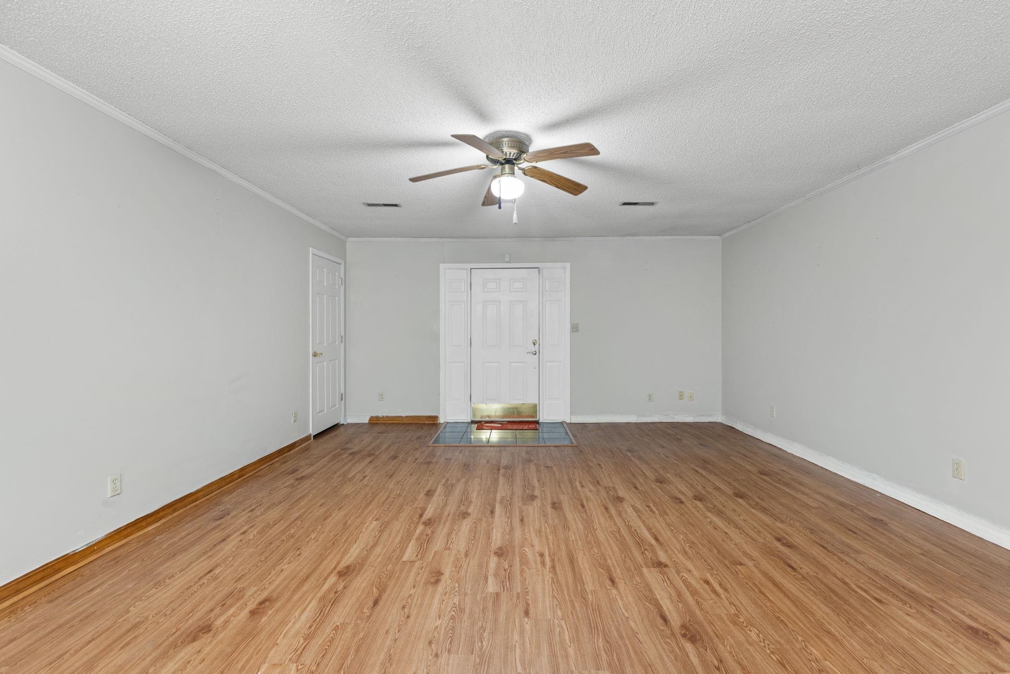 310 County Road 638 Corinth, MS 38834 - Photo 9 of 40 Unfurnished living room with a textured ceiling, light wood finished floors, a ceiling fan, and crown molding