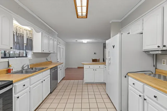 a kitchen with white cabinets a sink a stove and refrigerator