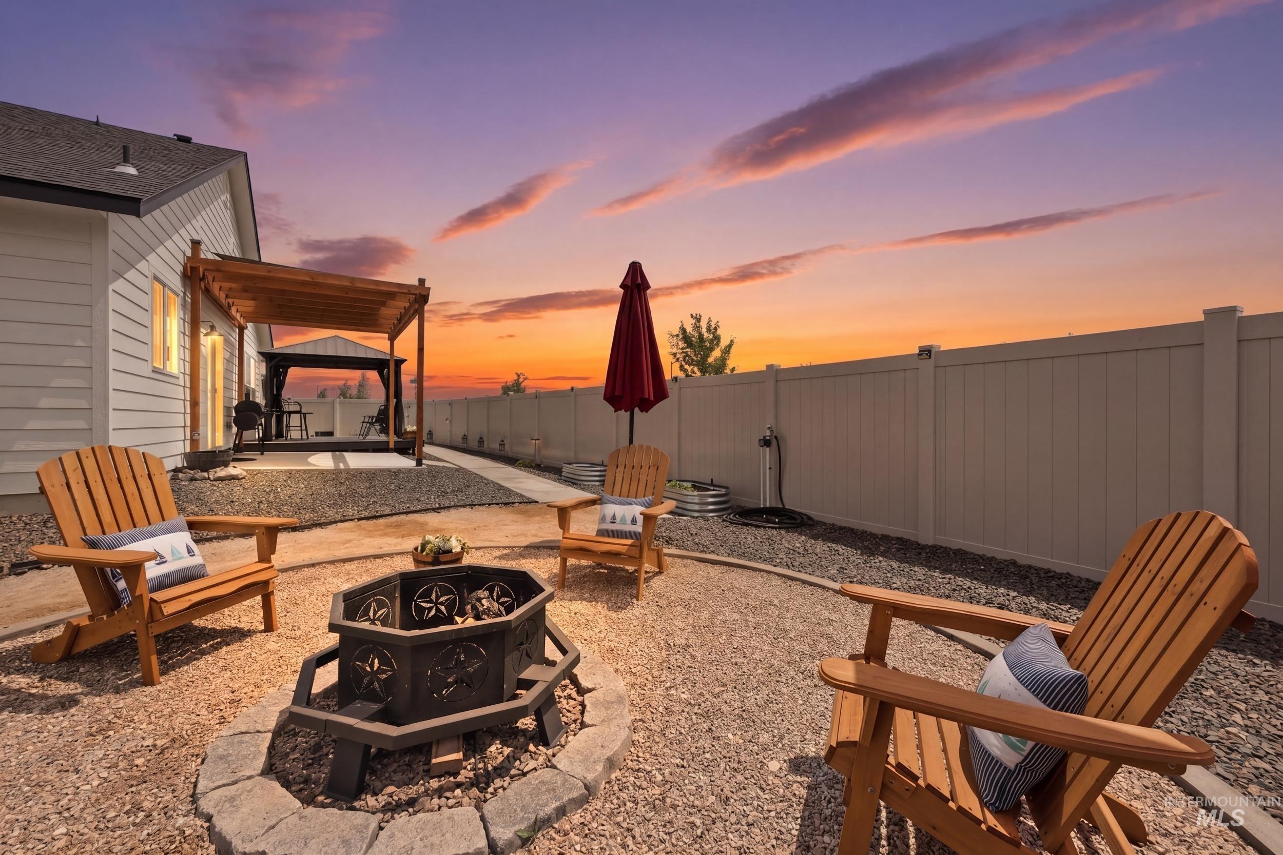 3665 W Lane Meridian, ID 83642 - Photo 2 of 42 Gravel patio featuring a fire pit with stone surround, a wooden pergola, and a covered outdoor seating area