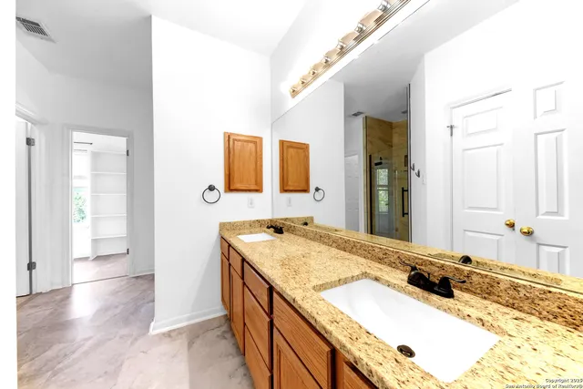 a bathroom with a granite countertop double vanity sink and a mirror