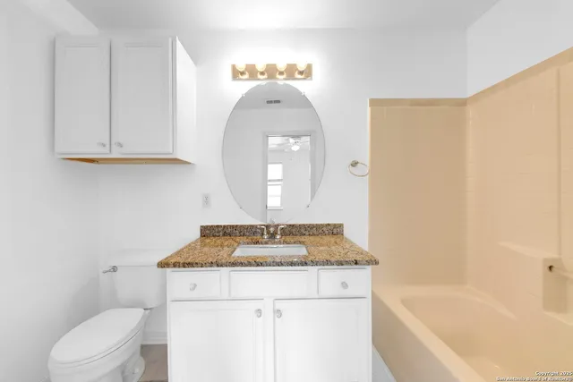 a bathroom with a granite countertop sink a toilet and bathtub
