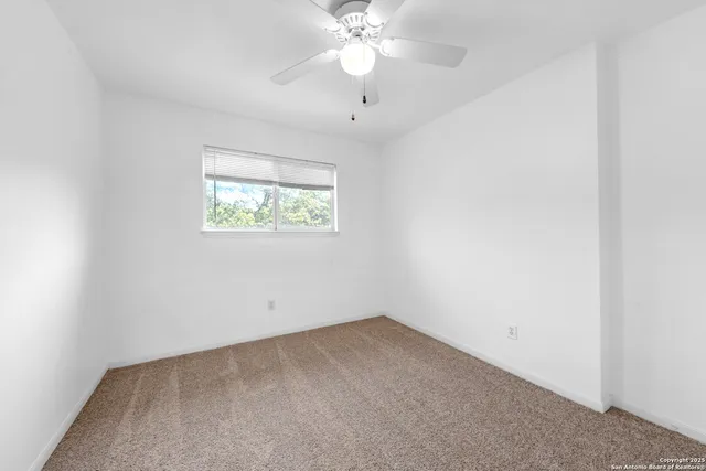an empty room with a window and a fan