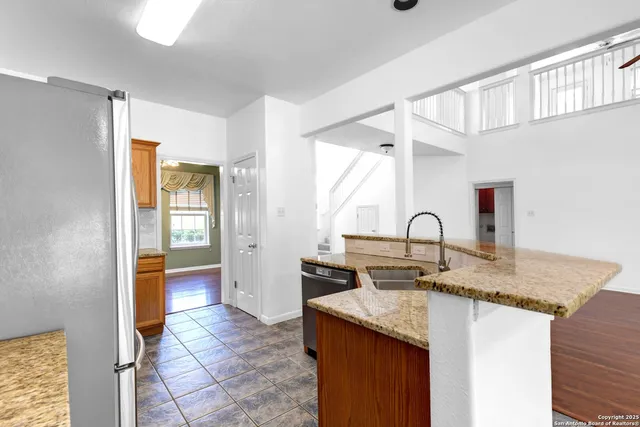 a kitchen with stainless steel appliances granite countertop a sink and a refrigerator