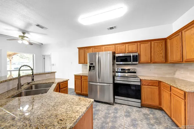 a kitchen with stainless steel appliances granite countertop a stove refrigerator sink and cabinets