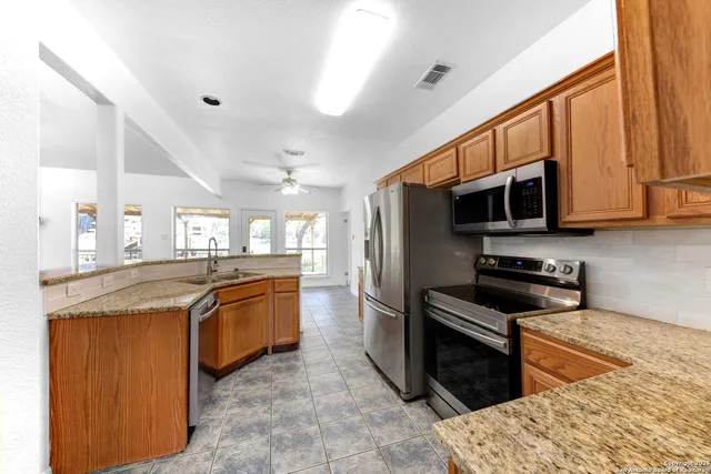 a kitchen with stainless steel appliances granite countertop a stove top oven microwave and refrigerator