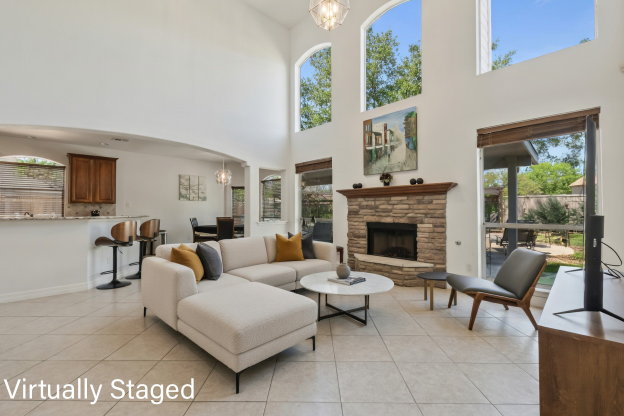 8903 Halder Cove Austin, TX 78717 - Photo 5 of 26 Living room with arched walkways, a stone fireplace, light tile patterned floors, suspended lighting, and a high ceiling