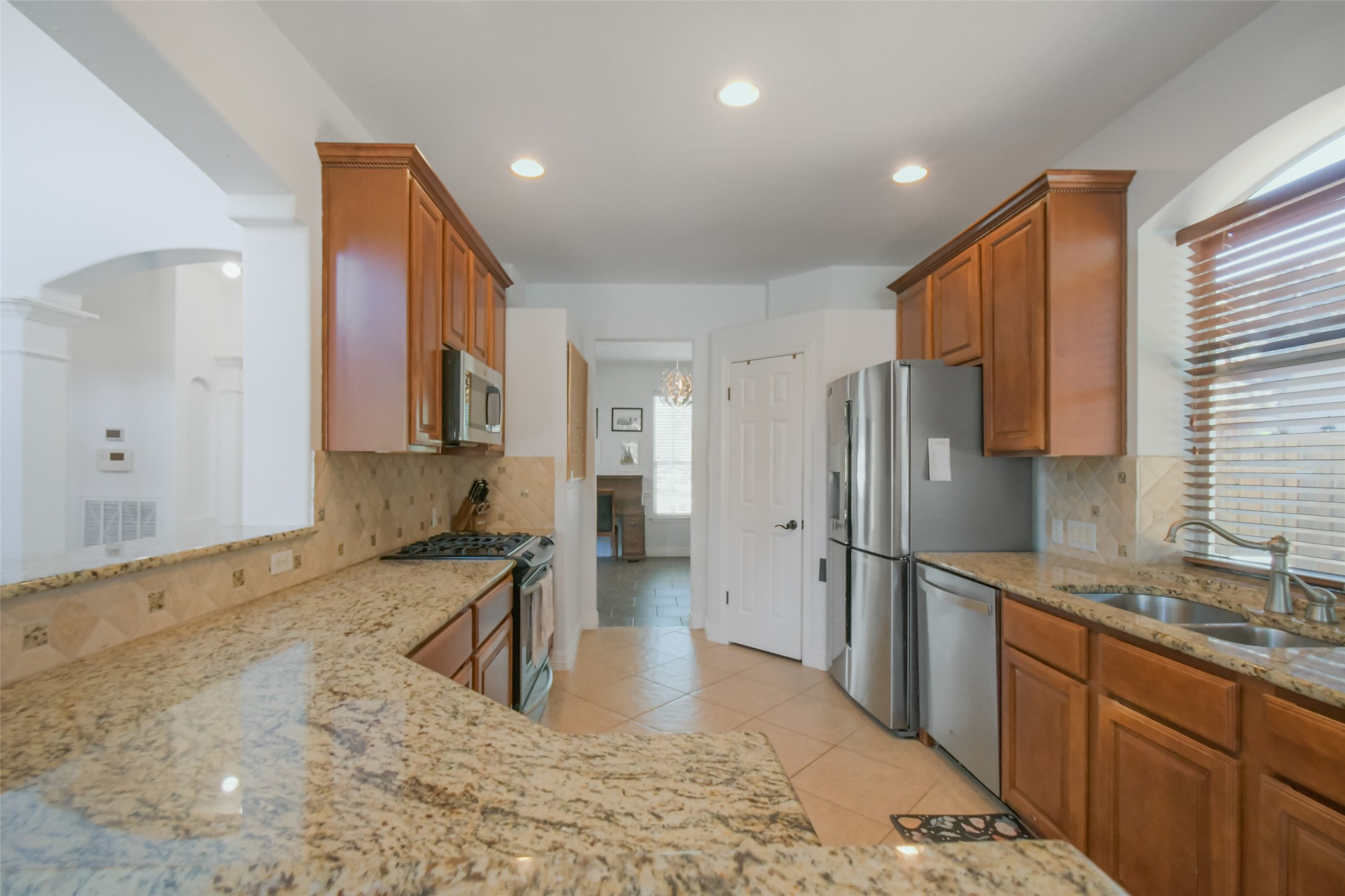 8903 Halder Cove Austin, TX 78717 - Photo 7 of 26 Kitchen with granite stone counters, stainless steel appliances, arched walkways, wood finish cabinets, and recessed lighting