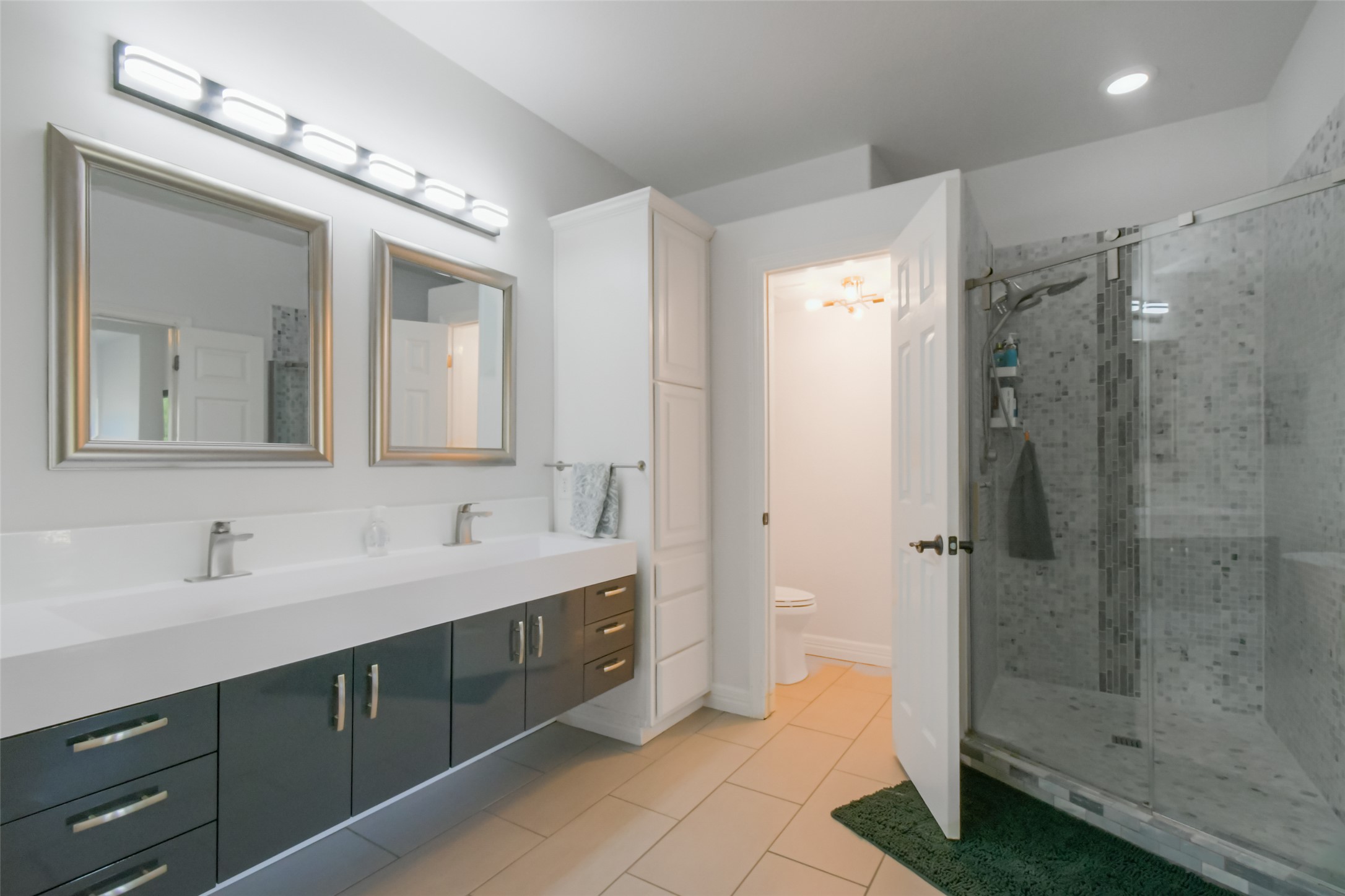 8903 Halder Cove Austin, TX 78717 - Photo 10 of 26 Bathroom with double vanity, a shower stall, and pebbled stone floors