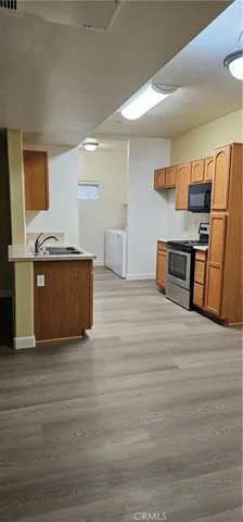 a view of kitchen with stainless steel appliances wooden floor large window and wooden floor
