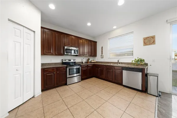 a large kitchen with granite countertop a stove top oven microwave and refrigerator