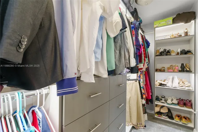 a view of walk in closet with clothes and shoes