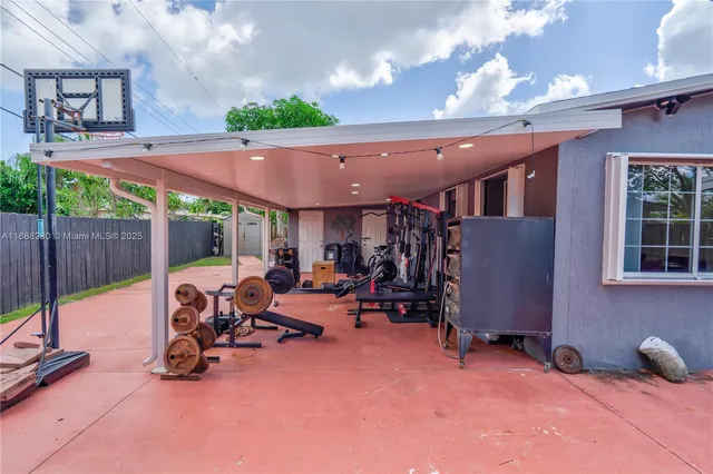 a view of a patio with table and chairs under an umbrella with a small yard