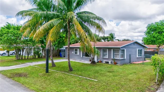 front view of a house with a yard and palm trees