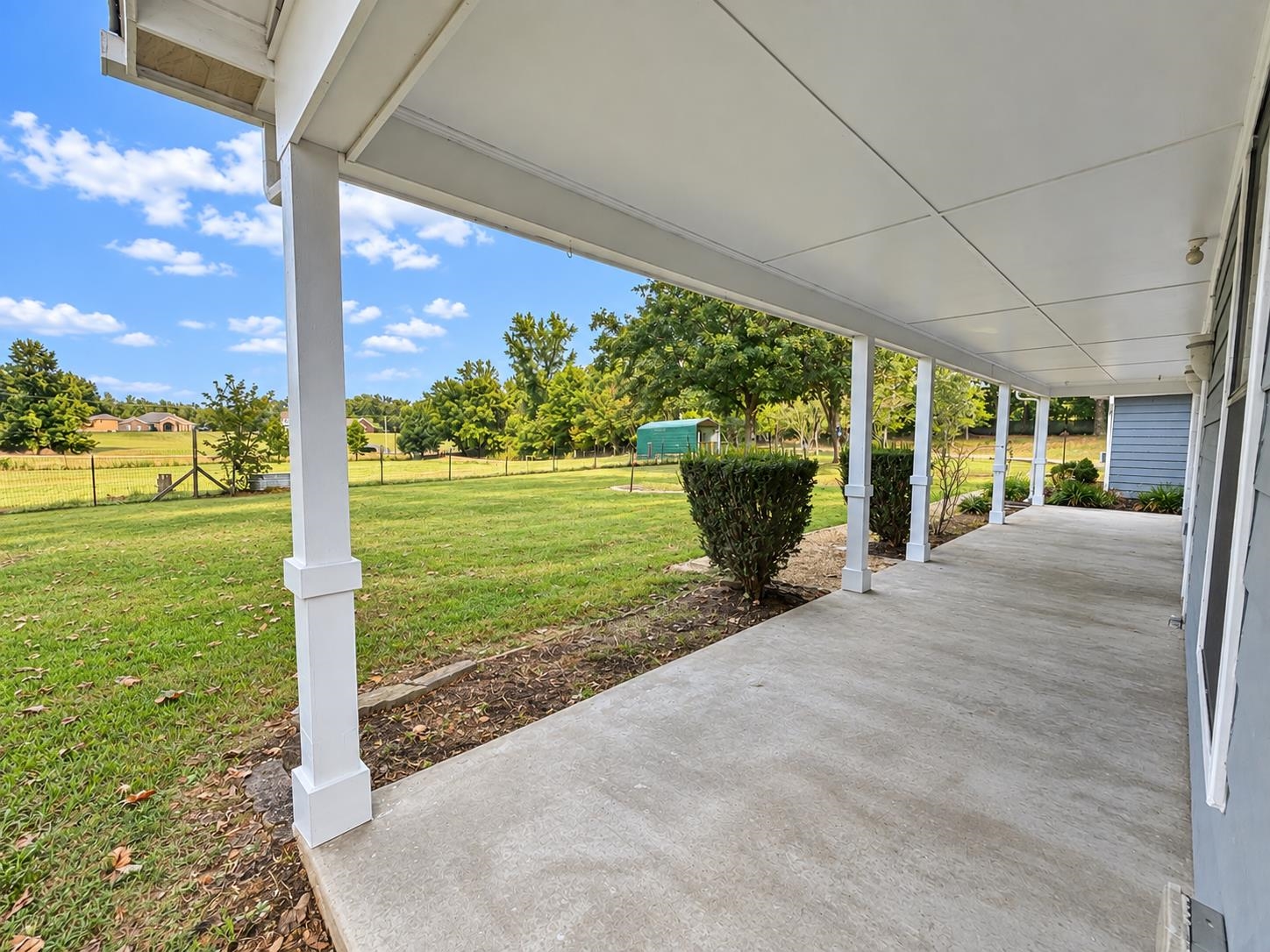 3771 West Union Road Millington, TN 38053 - Photo 3 of 16 Expansive covered porch featuring white support columns, a concrete surface, and surrounding green lawn
