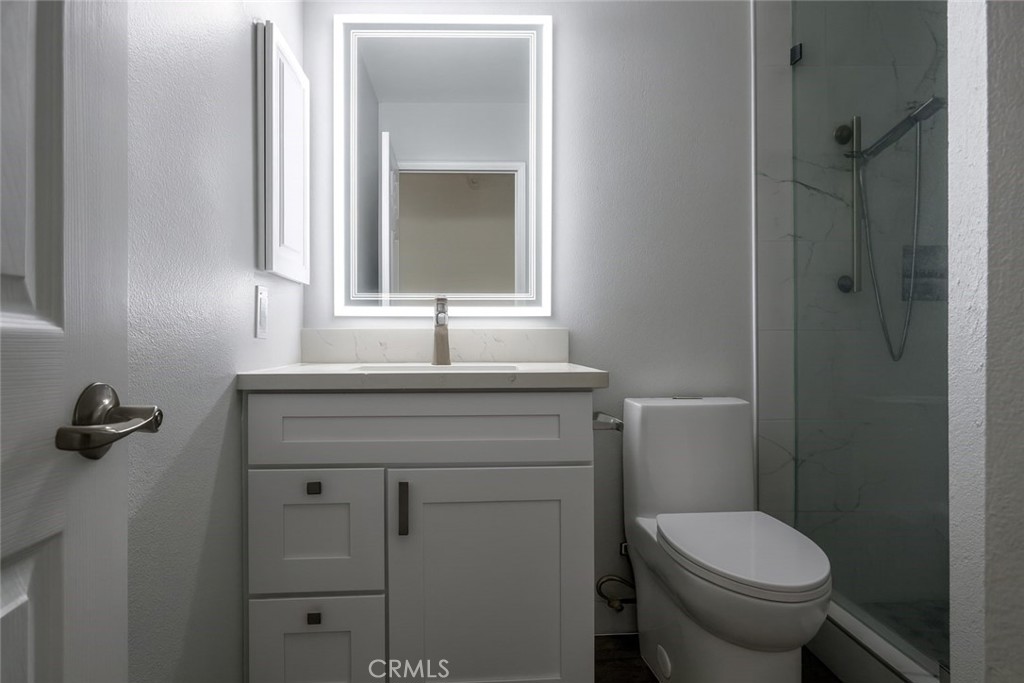 5114 West 1st Street, Unit C Santa Ana, CA 92703 - Photo 21 of 26 a bathroom with a granite countertop toilet sink and mirror