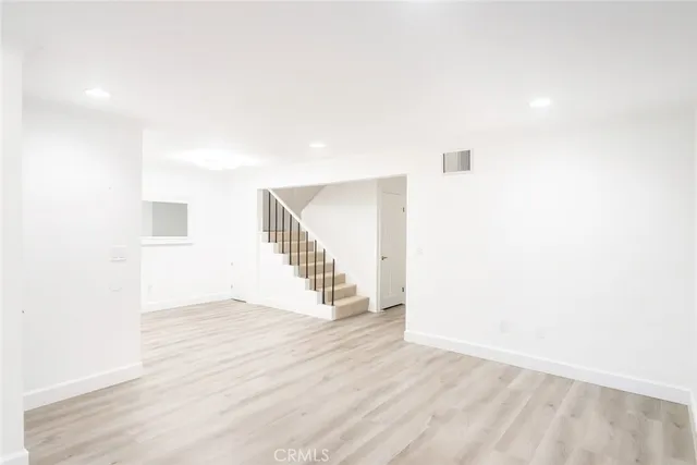 a view of a big room with wooden floor and windows