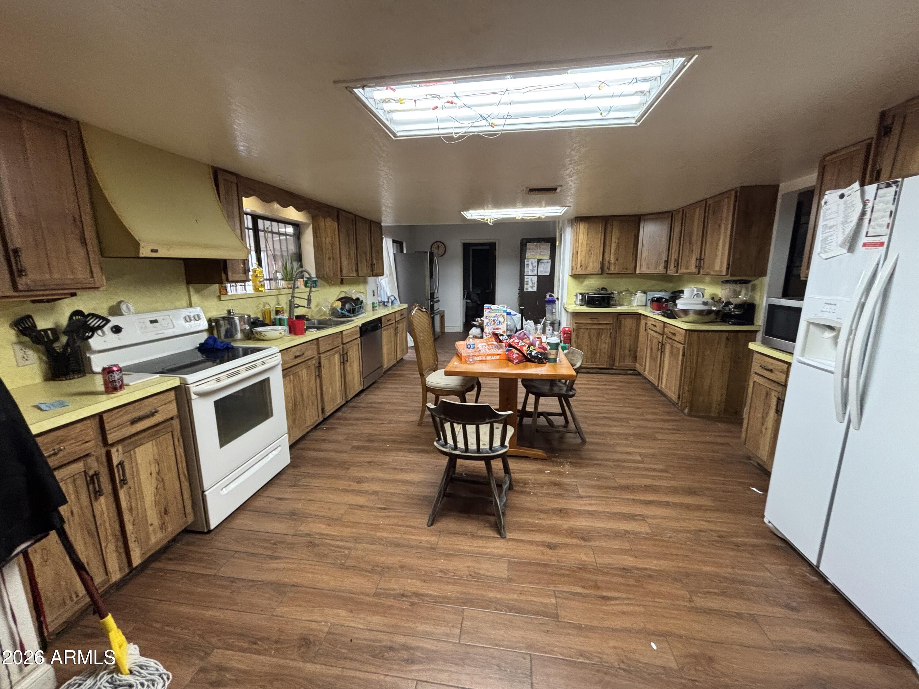 4934 West Fallen Leaf Lane Glendale, AZ 85310 - Photo 9 of 24 a kitchen with stainless steel appliances a stove a sink dishwasher a refrigerator white cabinets with wooden floor