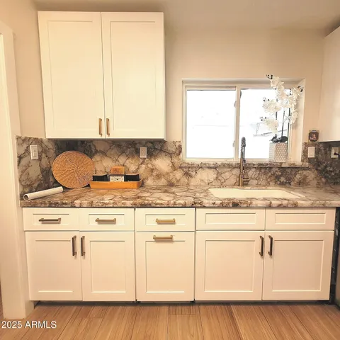 a kitchen with granite countertop white cabinets white appliances wooden floor and a large window