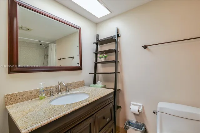 a bathroom with a granite countertop sink toilet and a mirror