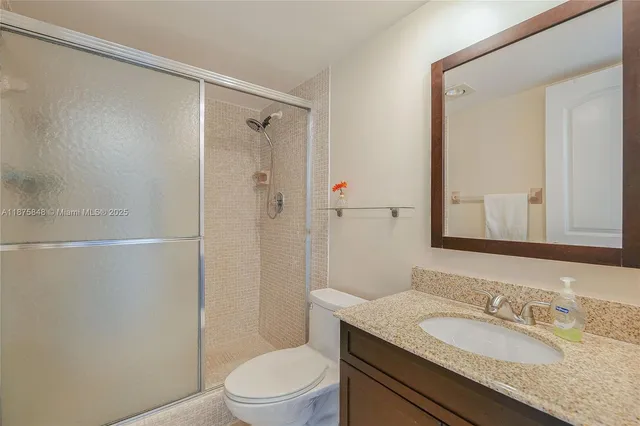 a bathroom with a granite countertop sink toilet and shower