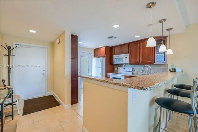 a kitchen with granite countertop kitchen island stainless steel appliances a sink and a refrigerator