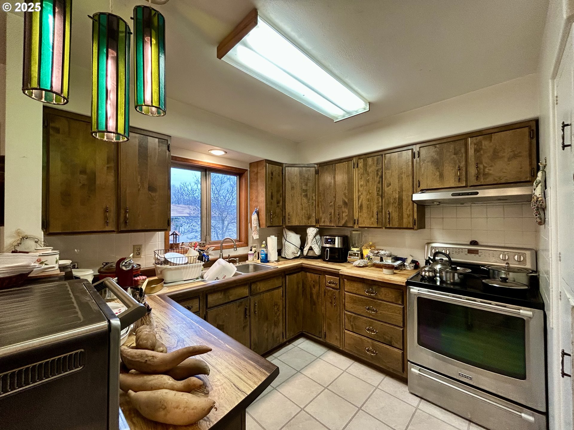 917 Myrtle Street The Dalles, OR 97058 - Photo 13 of 22 a kitchen with a sink a stove cabinets and a window