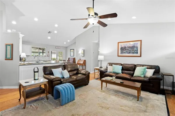 a living room with furniture kitchen view and a chandelier