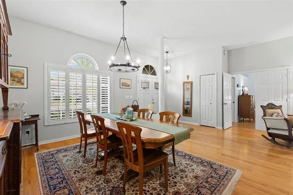 a view of a dining room and livingroom with furniture wooden floor a rug a rug a fireplace and a chandelier