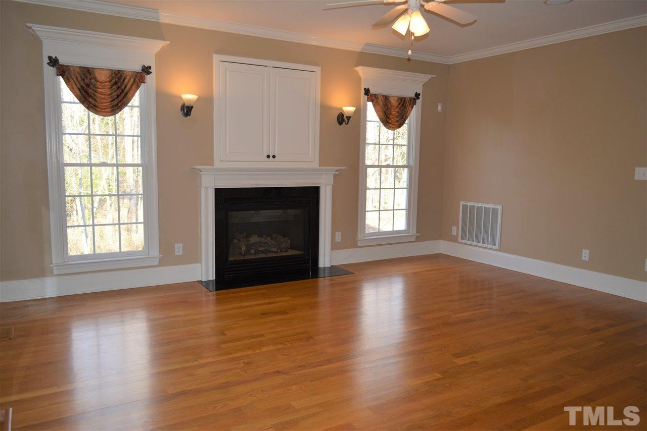 1316 Wynncrest Court Raleigh, NC 27603 - Photo 7 of 30 an empty room with wooden floor fireplace and windows