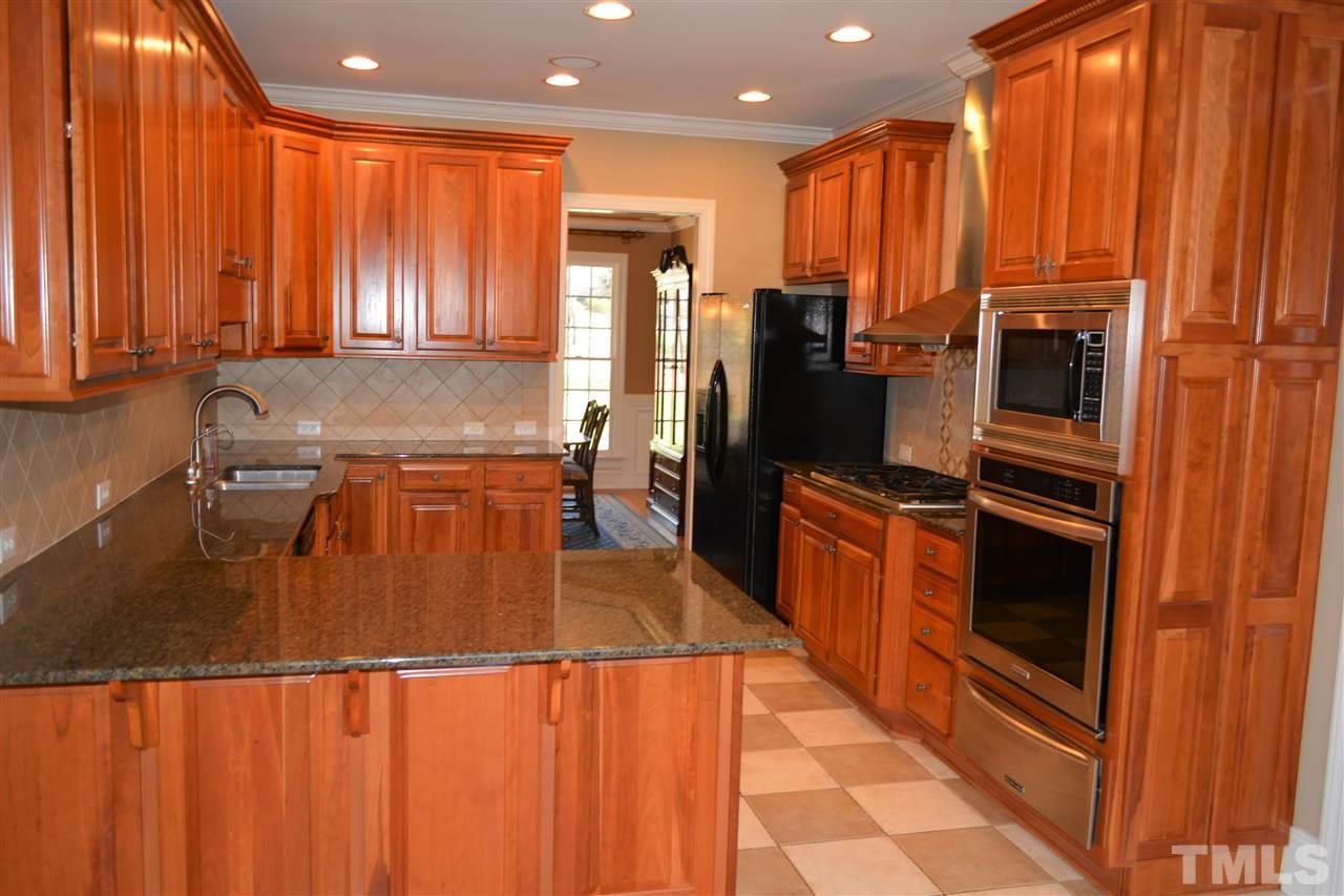 1316 Wynncrest Court Raleigh, NC 27603 - Photo 10 of 30 a kitchen with stainless steel appliances granite countertop a refrigerator a stove and a sink with wooden cabinets
