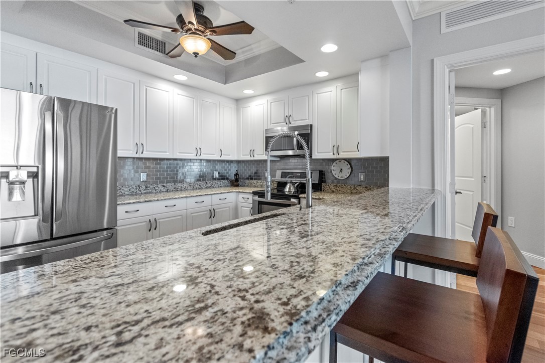 2090 West First Street, Unit I409 Fort Myers, FL 33901 - Photo 7 of 44 a large kitchen with kitchen island a large counter space a sink stainless steel appliances and cabinets