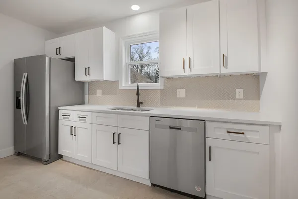 a kitchen with white cabinets and refrigerator