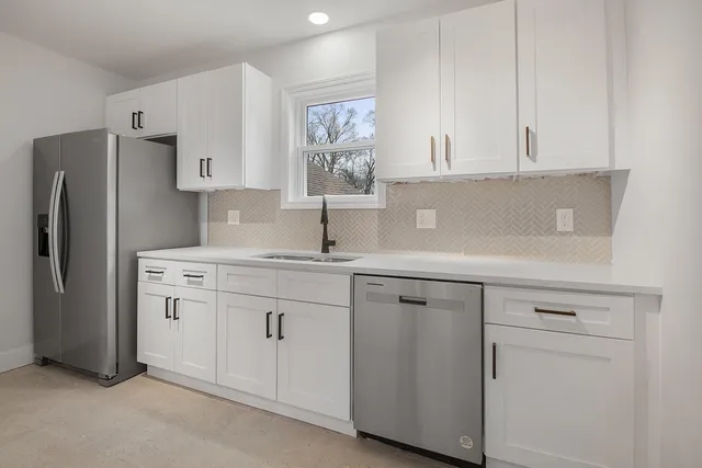 a kitchen with white cabinets and refrigerator