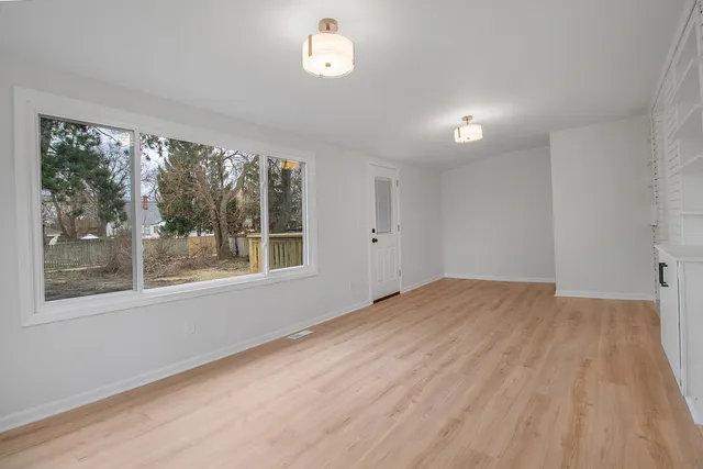 a view of an empty room with a window and wooden floor