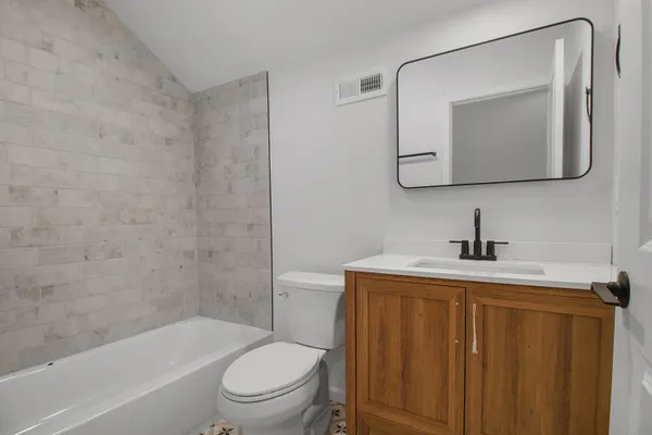 a bathroom with a toilet sink vanity tub and mirror