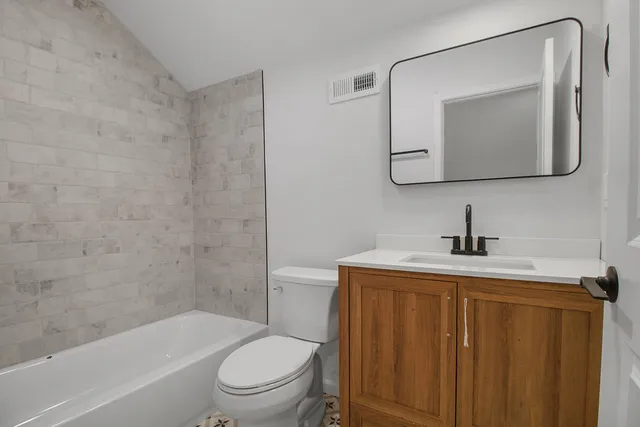 a bathroom with a toilet sink vanity tub and mirror