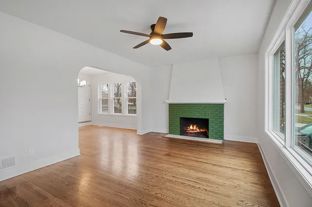 a view of an empty room with wooden floor fireplace and a window
