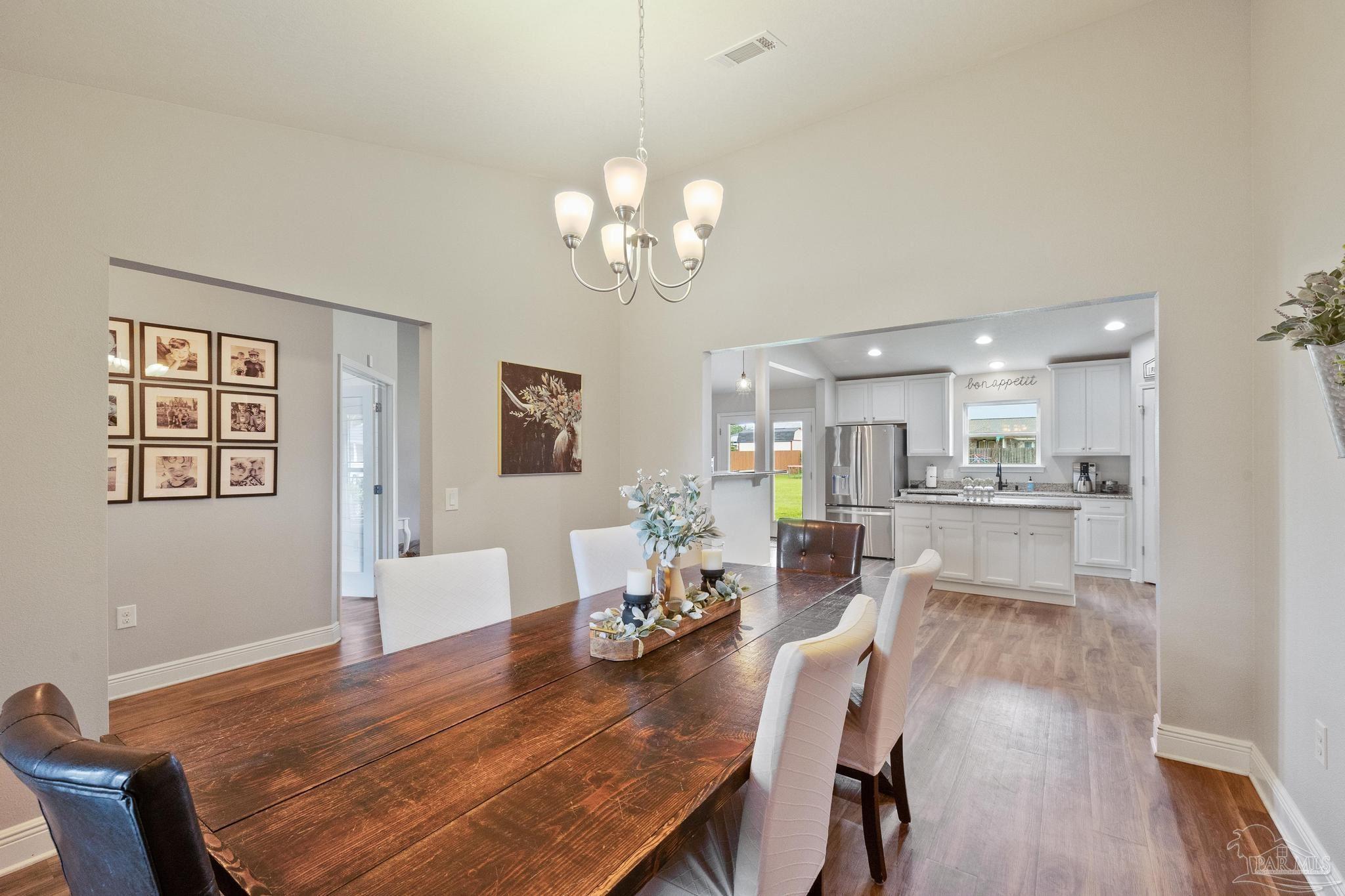 4037 Millwright Way Pace, FL 32571 - Photo 15 of 46 a view of a dining room with furniture a chandelier and wooden floor