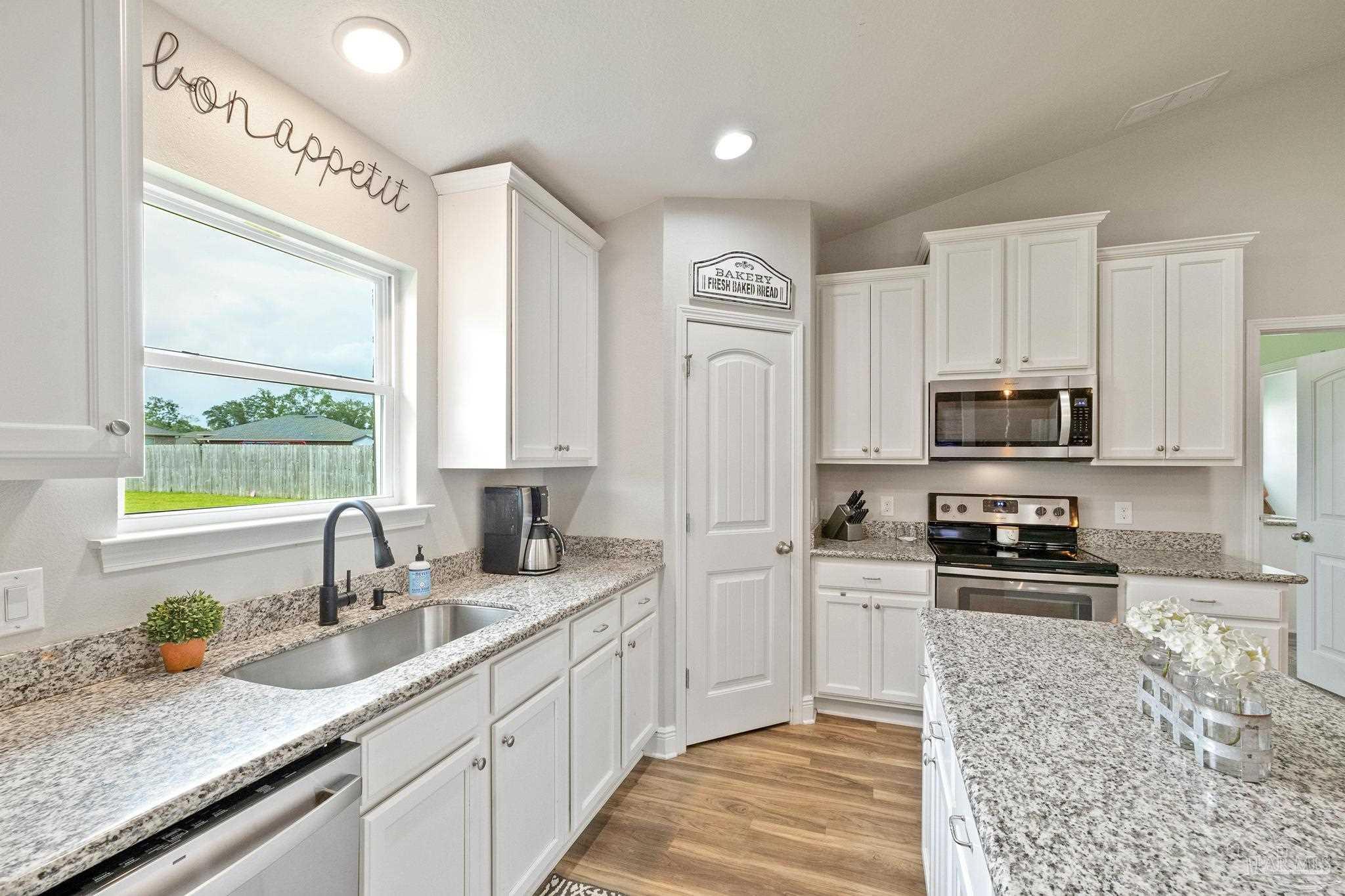4037 Millwright Way Pace, FL 32571 - Photo 23 of 46 a kitchen with stainless steel appliances granite countertop a sink a stove and a granite counter tops with wooden floors